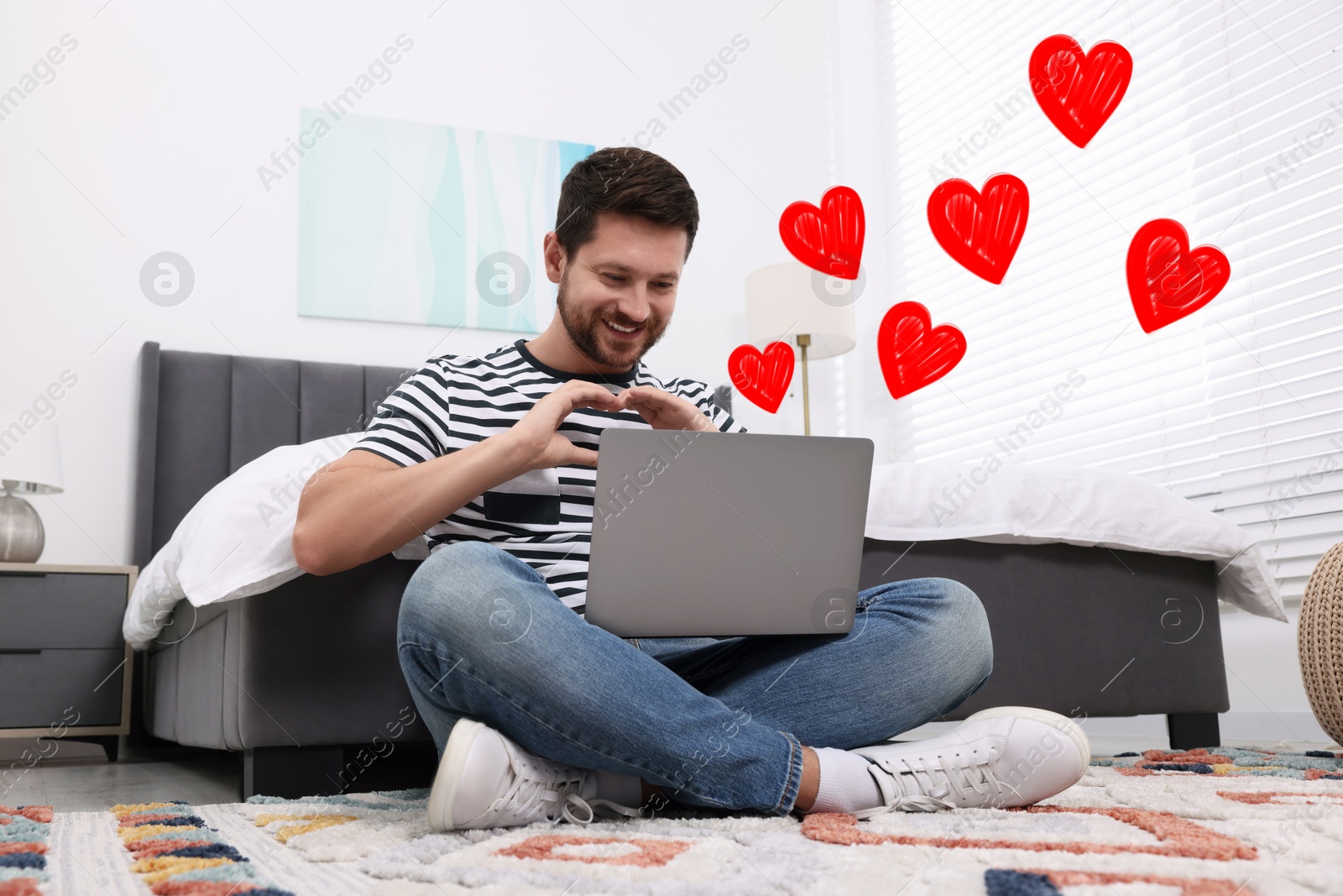 Image of Long distance relationship. Man having video chat with his loved one indoors. Red hearts near him