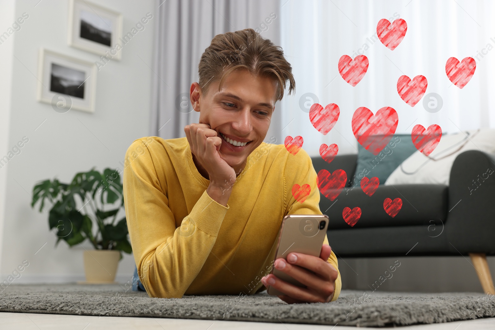 Image of Long distance relationship. Young man talking to his loved one via video chat indoors. Red hearts near him
