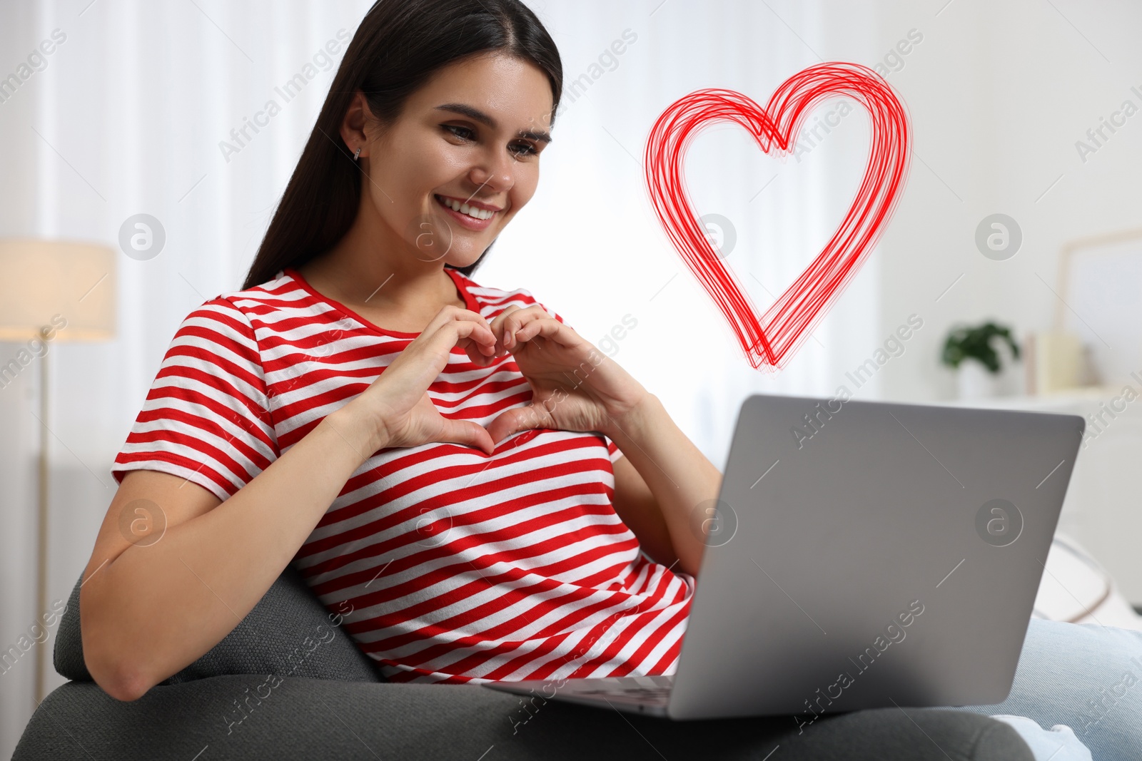 Image of Long distance relationship. Young woman having video chat with her loved one indoors. Red heart near her