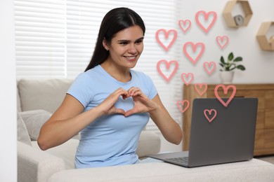 Image of Long distance relationship. Young woman having video chat with her loved one indoors. Pink hearts near her