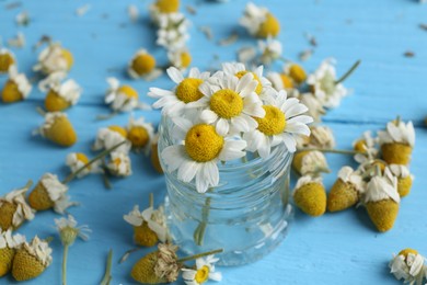 Photo of Chamomile flowers in glass jar on light blue table