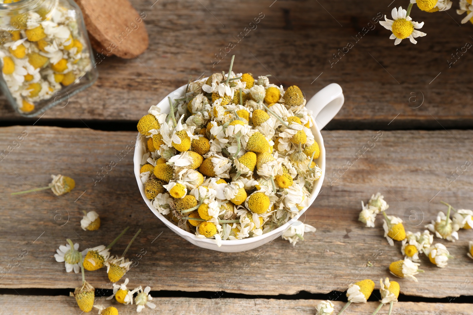 Photo of Chamomile flowers in cup on wooden table