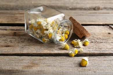 Chamomile flowers in glass jar on wooden table