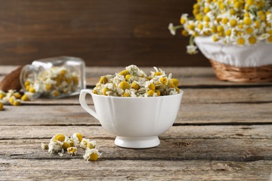 Photo of Chamomile flowers in cup on wooden table