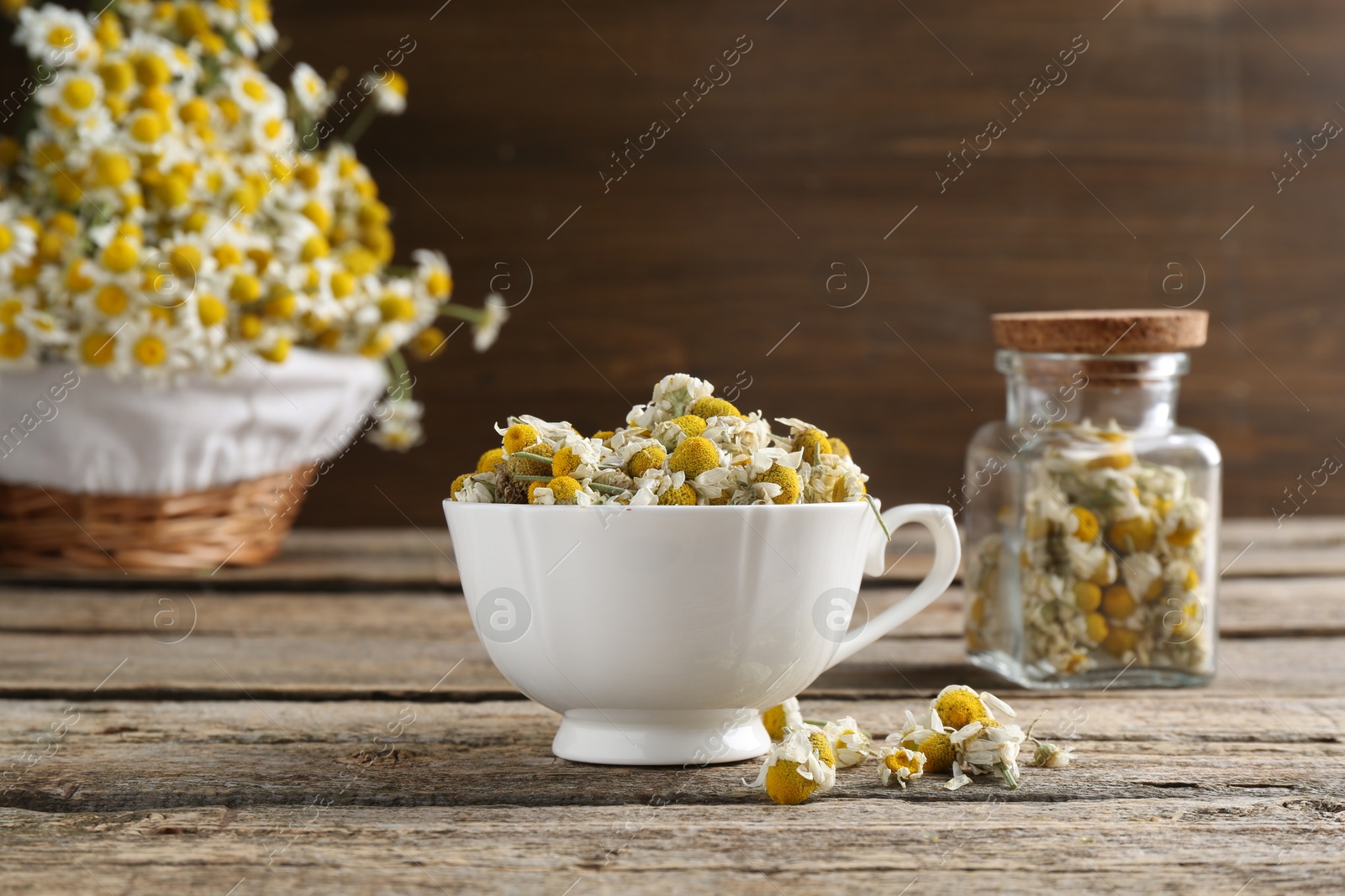 Photo of Chamomile flowers in cup on wooden table