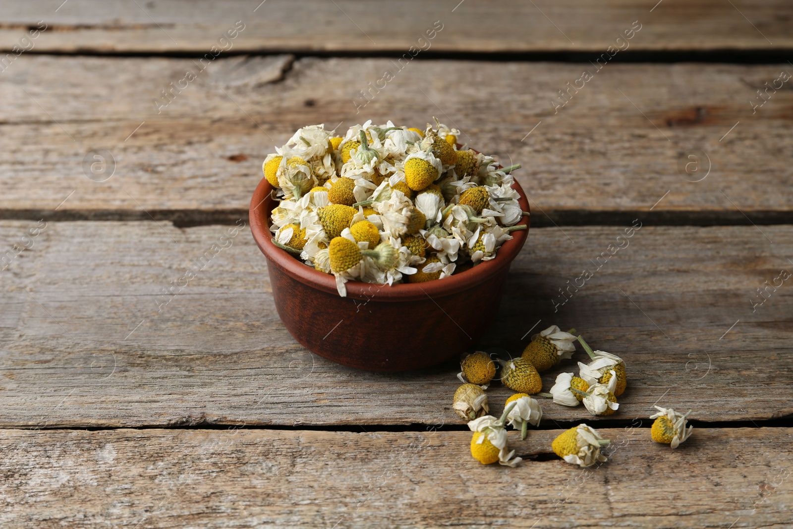 Photo of Chamomile flowers in bowl on wooden table