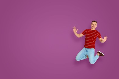 Image of Positive young man jumping on purple background. Space for text