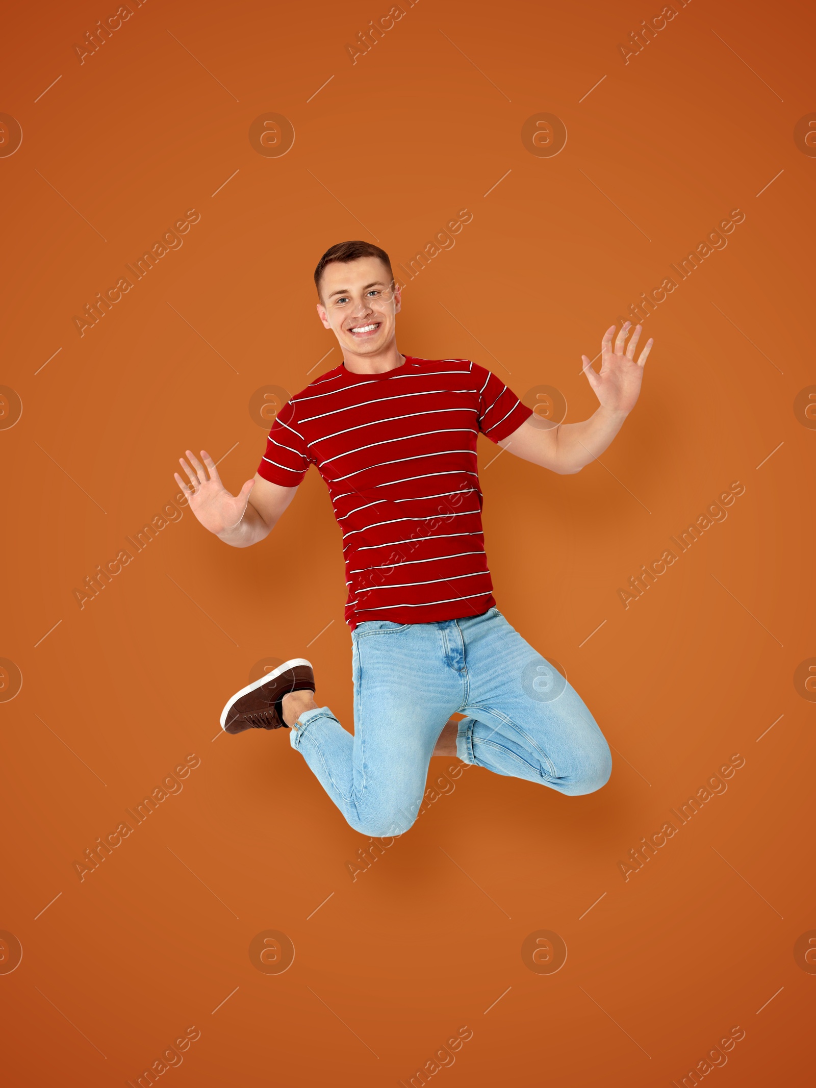 Image of Positive young man jumping on brown background