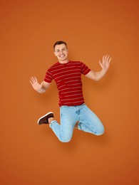 Positive young man jumping on brown background
