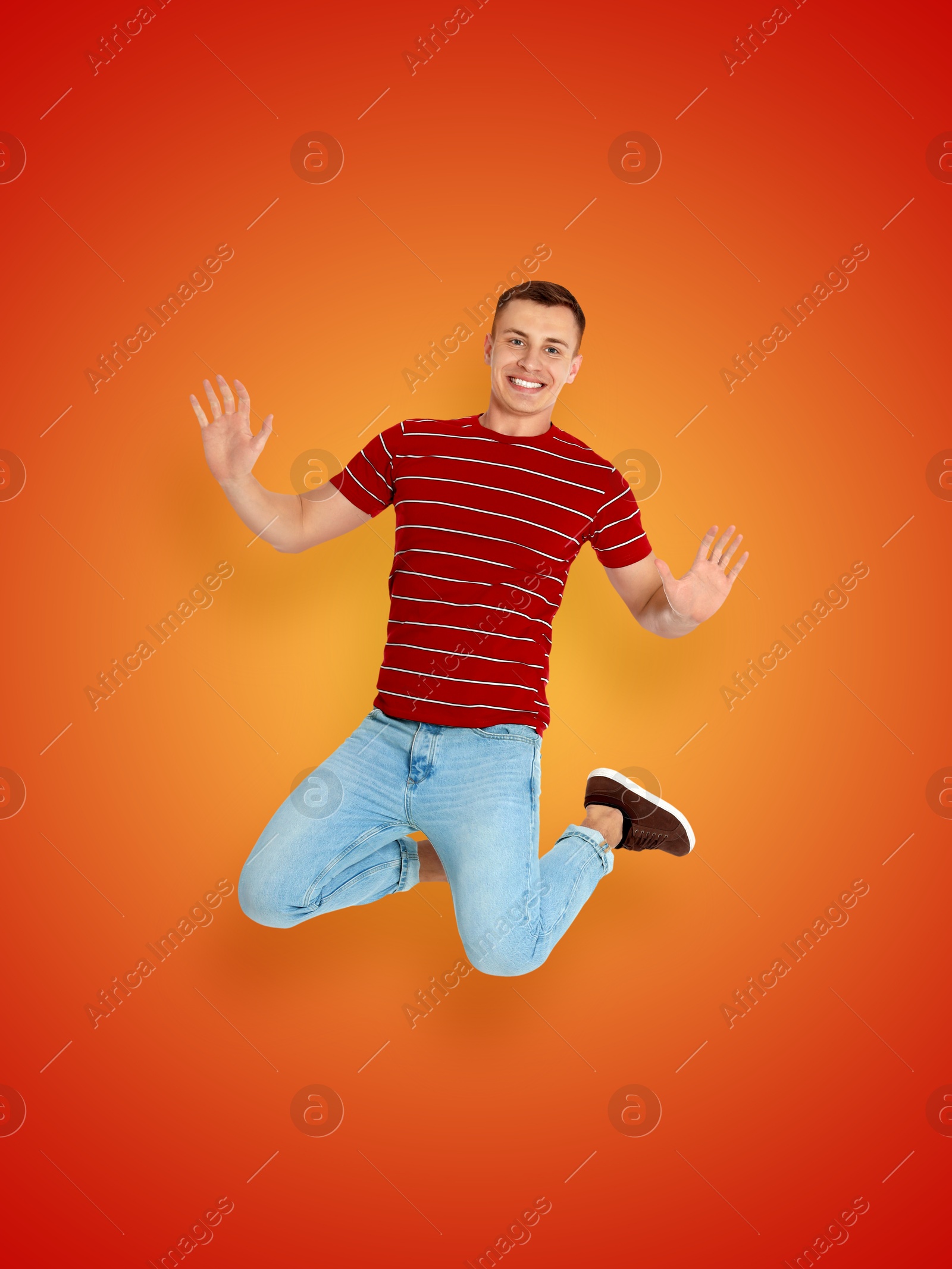 Image of Positive young man jumping on red orange gradient background