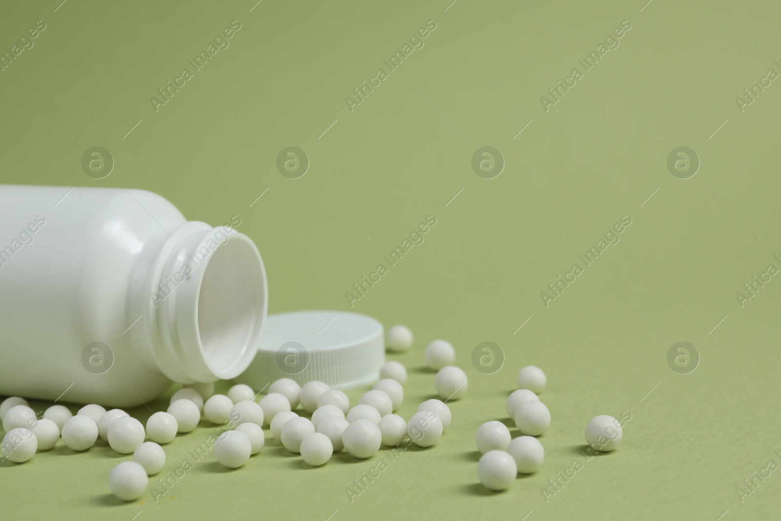 Photo of Homeopathic remedy and bottle on light green background. Space for text