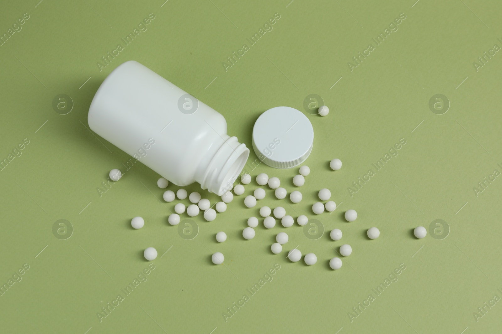 Photo of Homeopathic remedy and bottle on light green background, top view