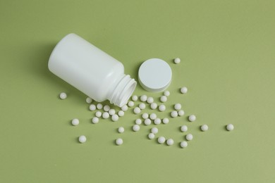 Photo of Homeopathic remedy and bottle on light green background, top view