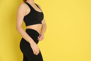 Photo of Woman with slim body posing on yellow background, closeup. Space for text