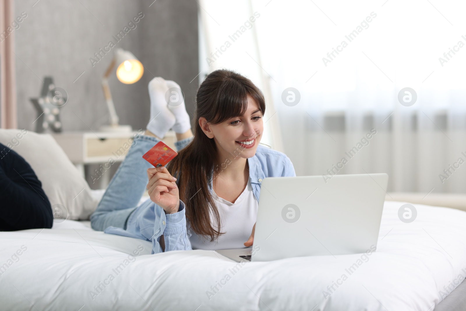 Photo of Online banking. Smiling woman with credit card and laptop paying purchase at home