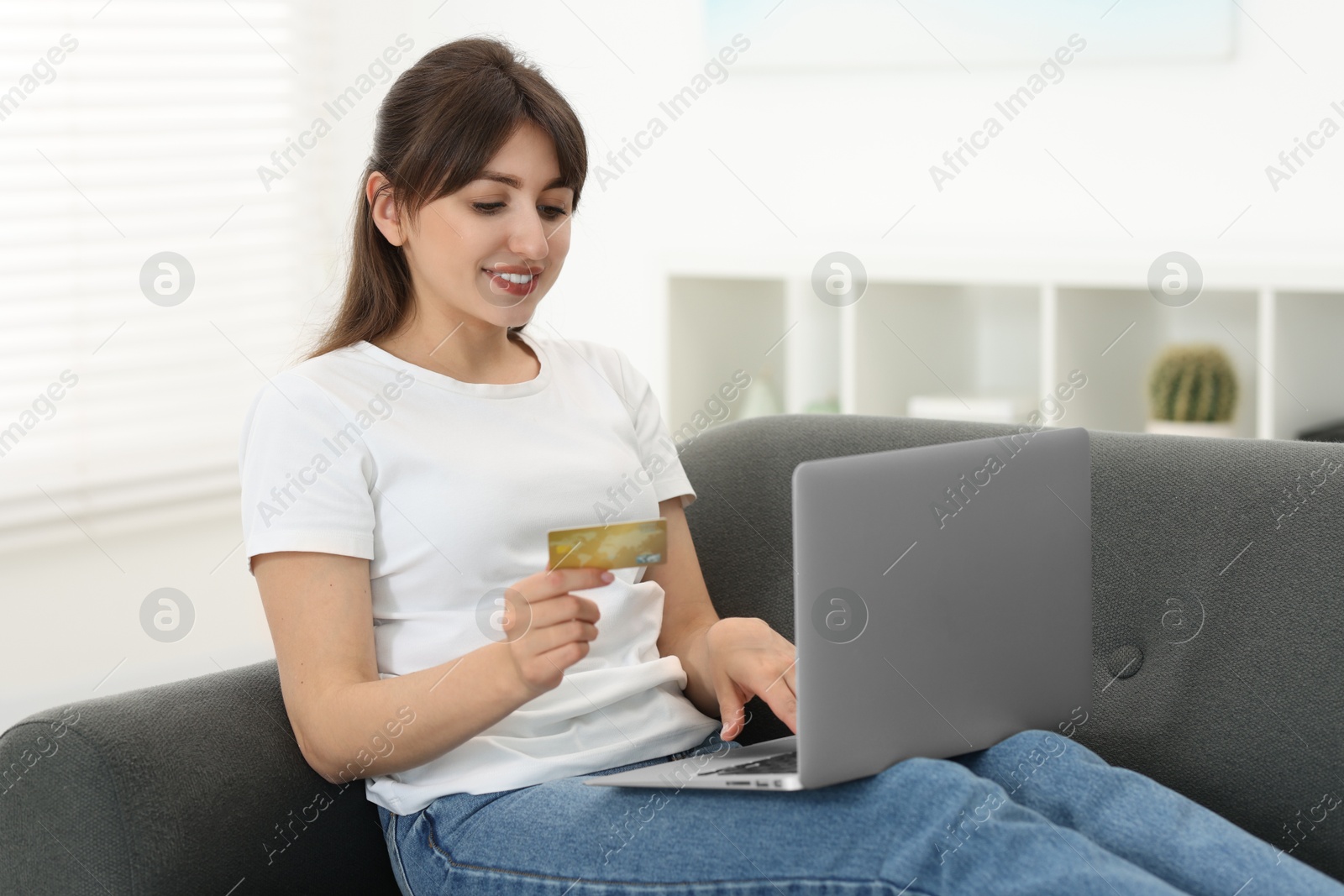 Photo of Online banking. Smiling woman with credit card and laptop paying purchase at home