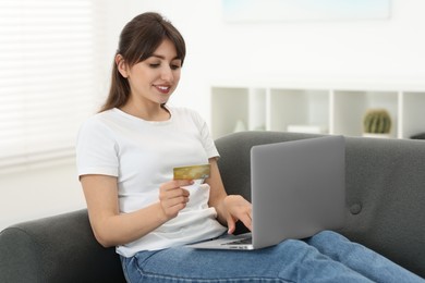 Online banking. Smiling woman with credit card and laptop paying purchase at home