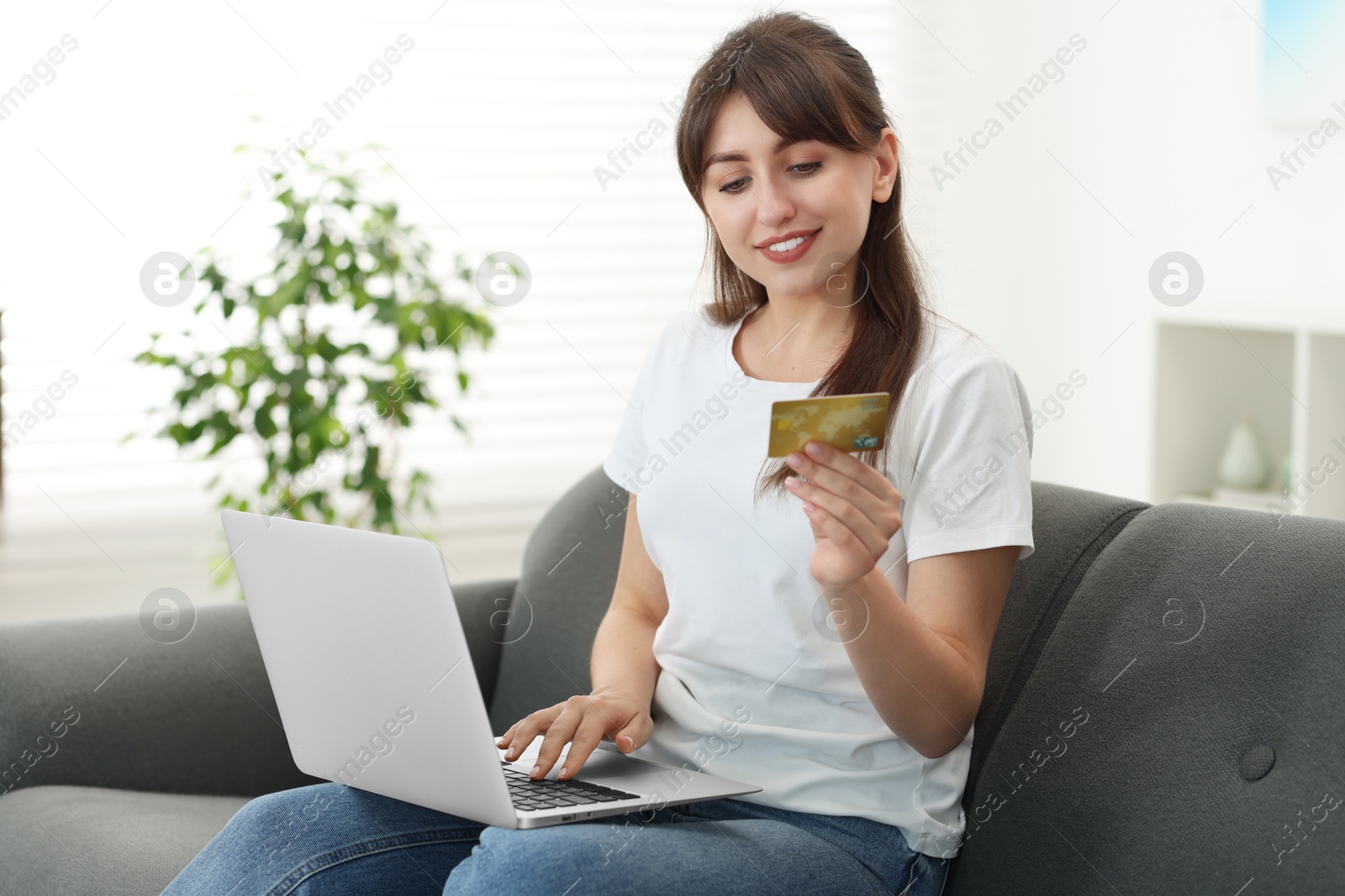 Photo of Online banking. Smiling woman with credit card and laptop paying purchase at home