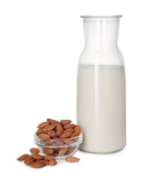 Glass jug of almond milk and almonds isolated on white