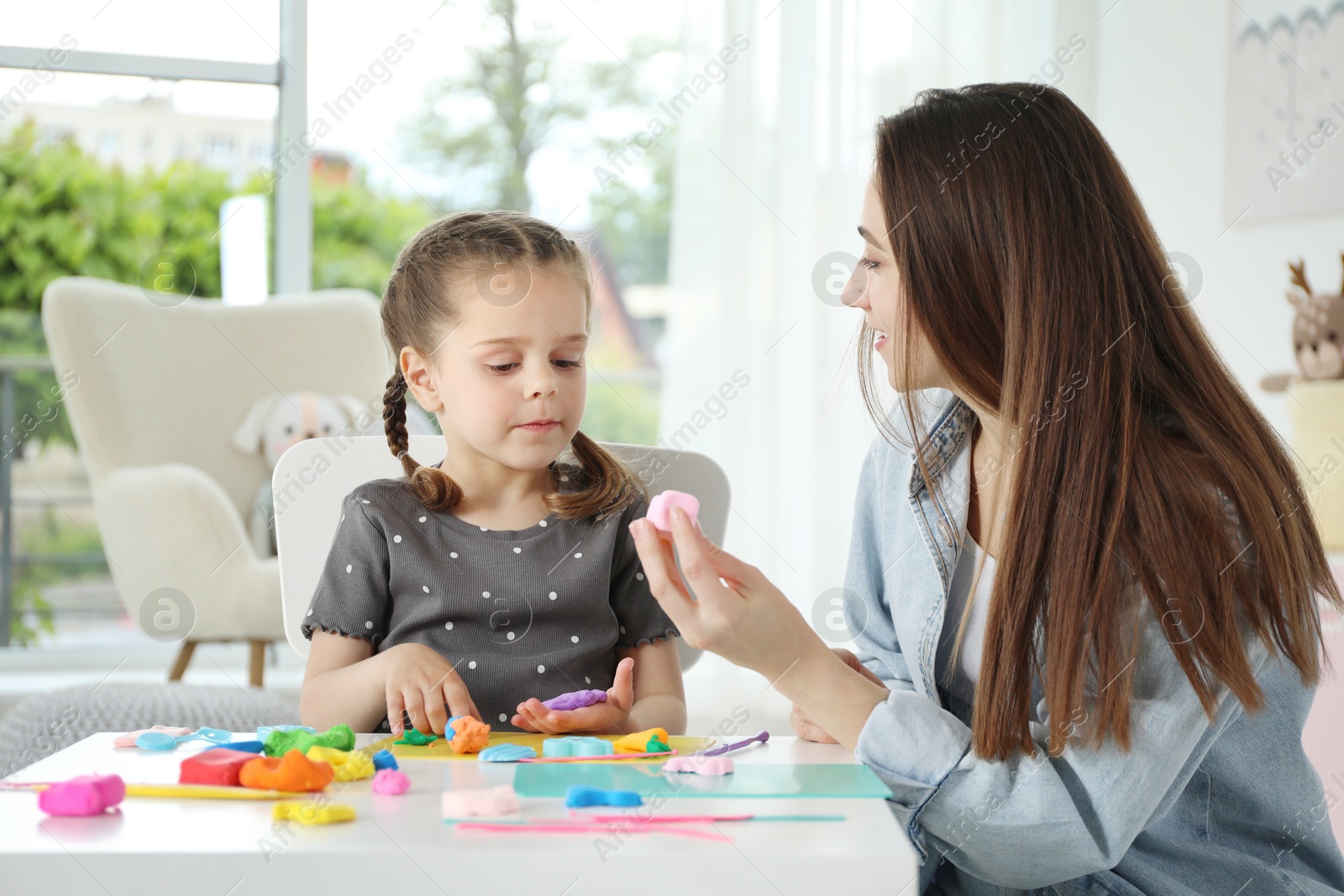 Photo of Mother and her daughter sculpting with play dough at table indoors