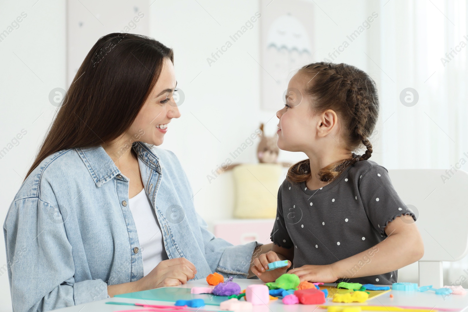 Photo of Play dough activity. Smiling mother with her daughter at table indoors