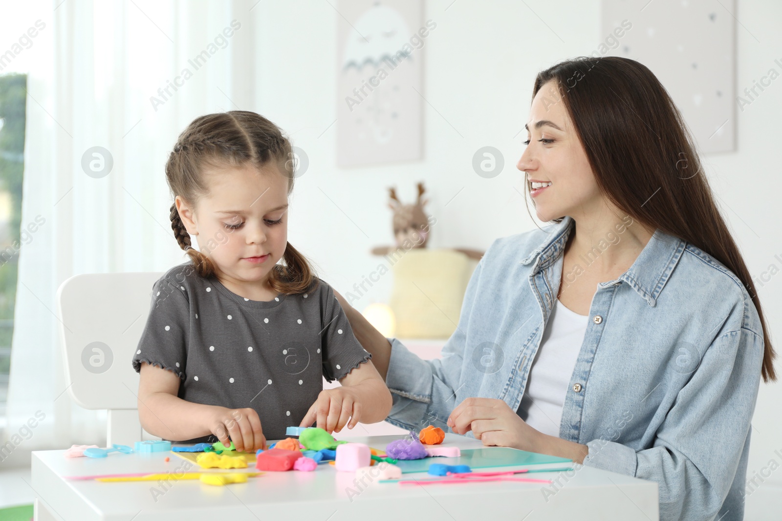 Photo of Play dough activity. Smiling mother with her daughter at table indoors