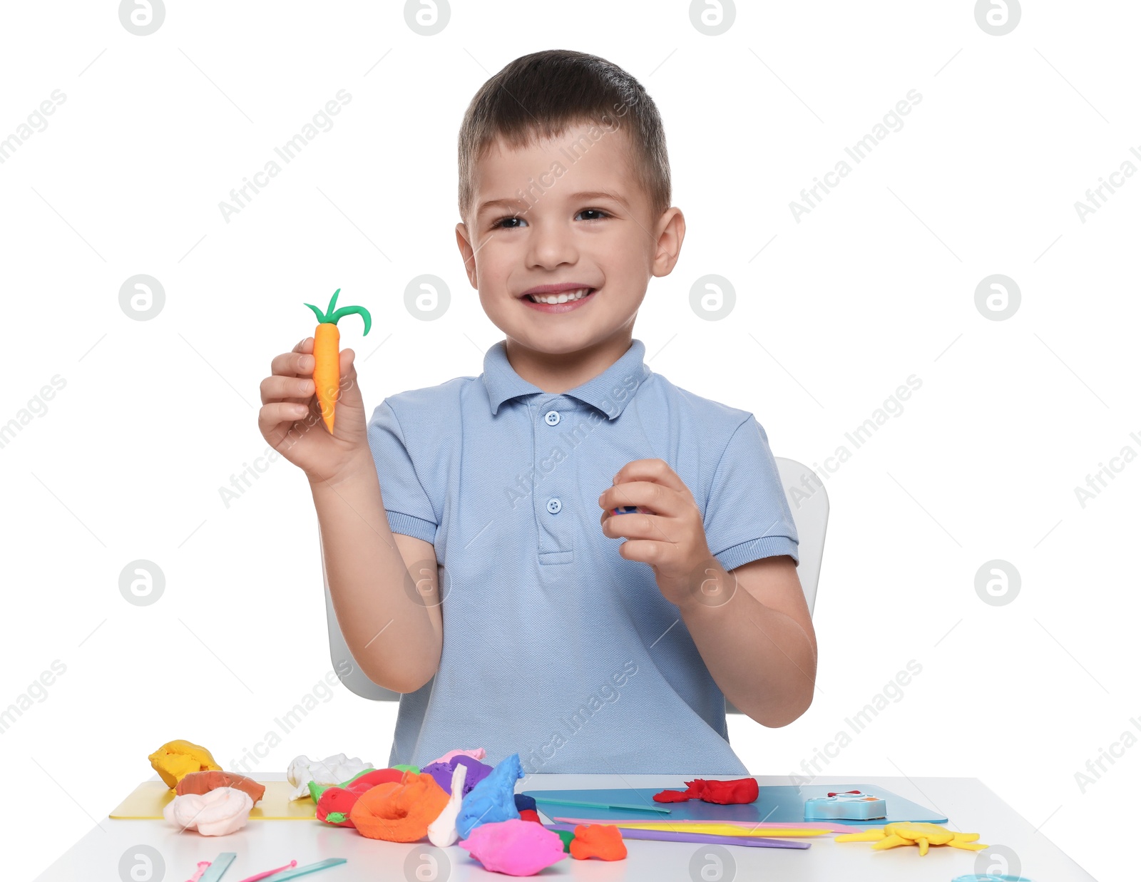 Photo of Smiling boy showing carrot made from play dough on white background