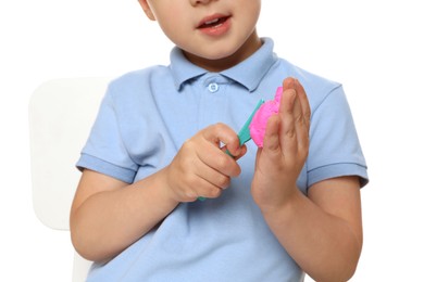 Photo of Little boy sculpting with play dough on white background, closeup