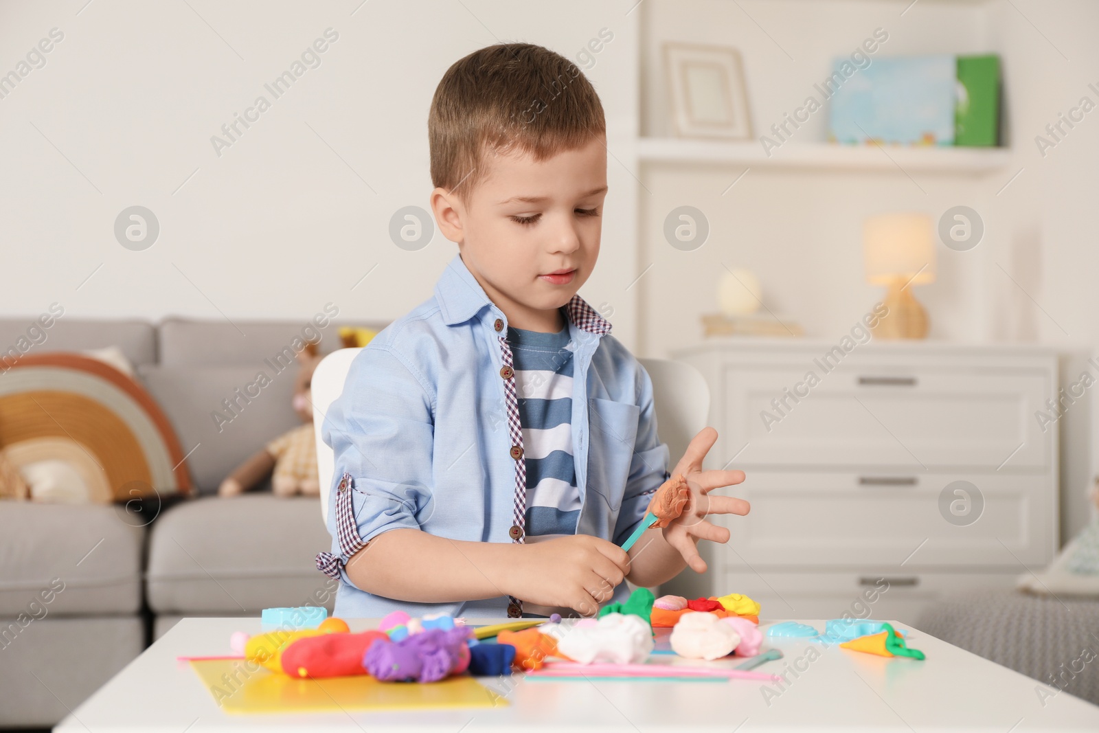 Photo of Little boy sculpting with play dough at table in kindergarten