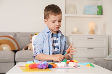 Little boy sculpting with play dough at table in kindergarten