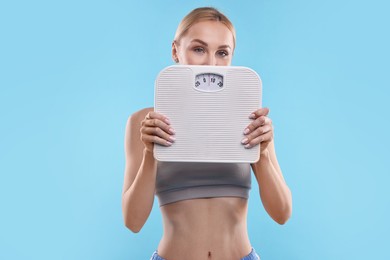 Photo of Woman with floor scale on light blue background