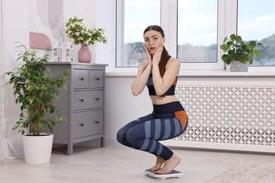 Photo of Worried woman on floor scale at home