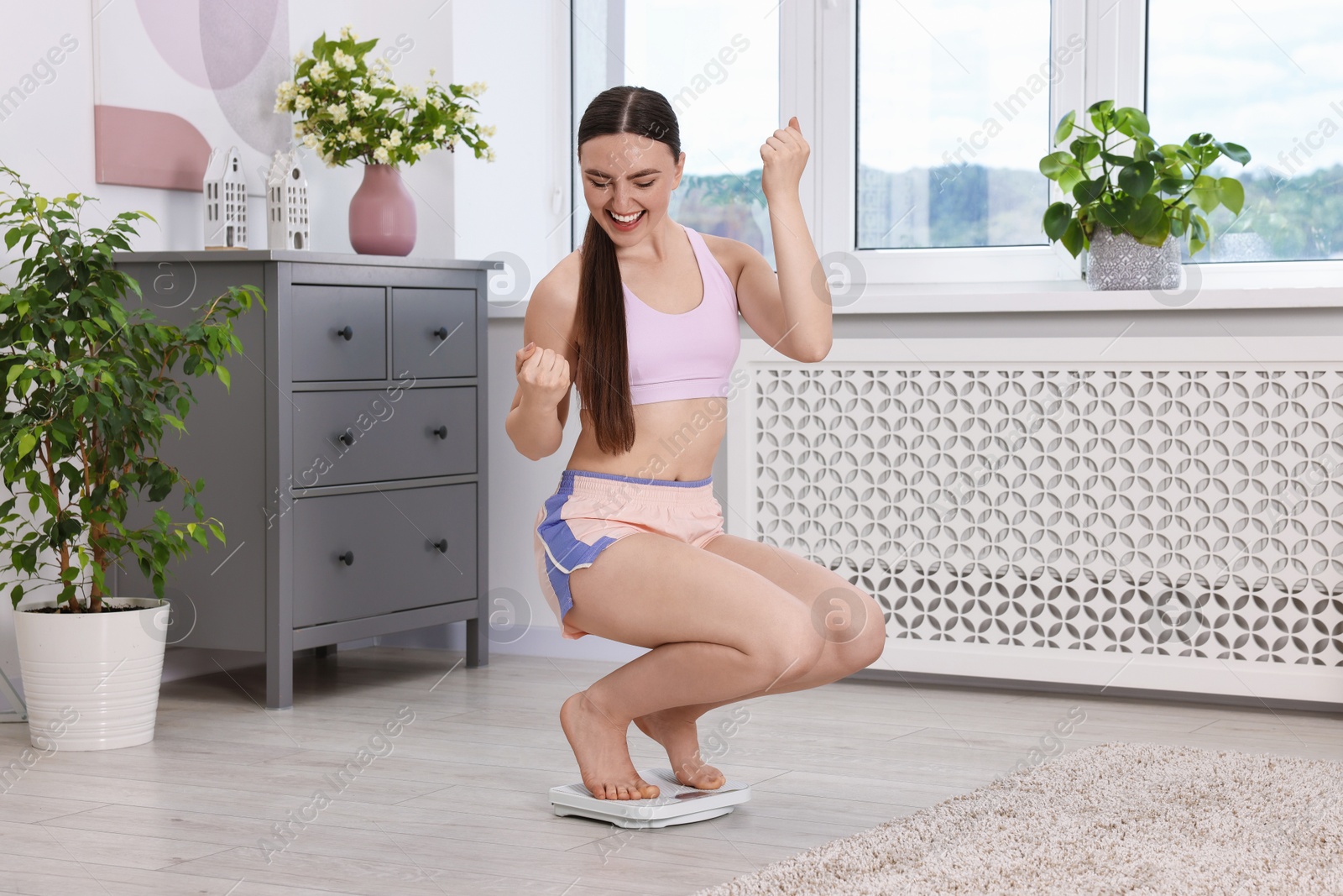 Photo of Happy woman on floor scale at home