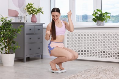 Happy woman on floor scale at home