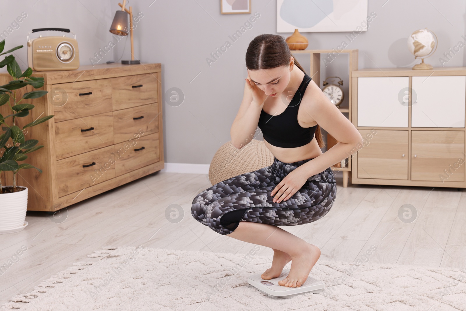 Photo of Woman measuring weight on floor scale at home