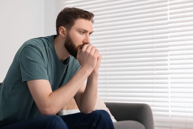 Photo of Loneliness concept. Sad man sitting on sofa at home, space for text