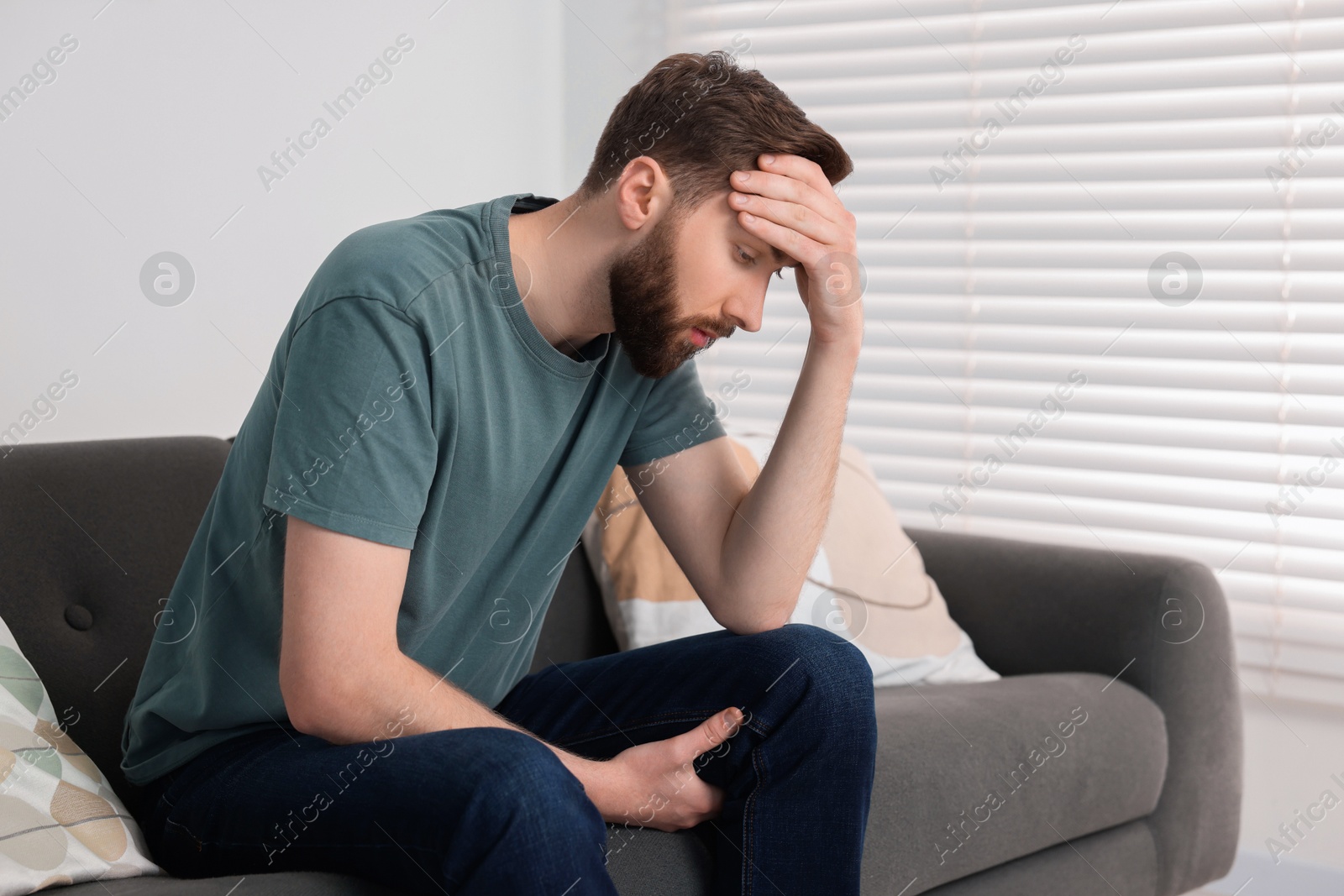 Photo of Loneliness concept. Sad man sitting on sofa at home