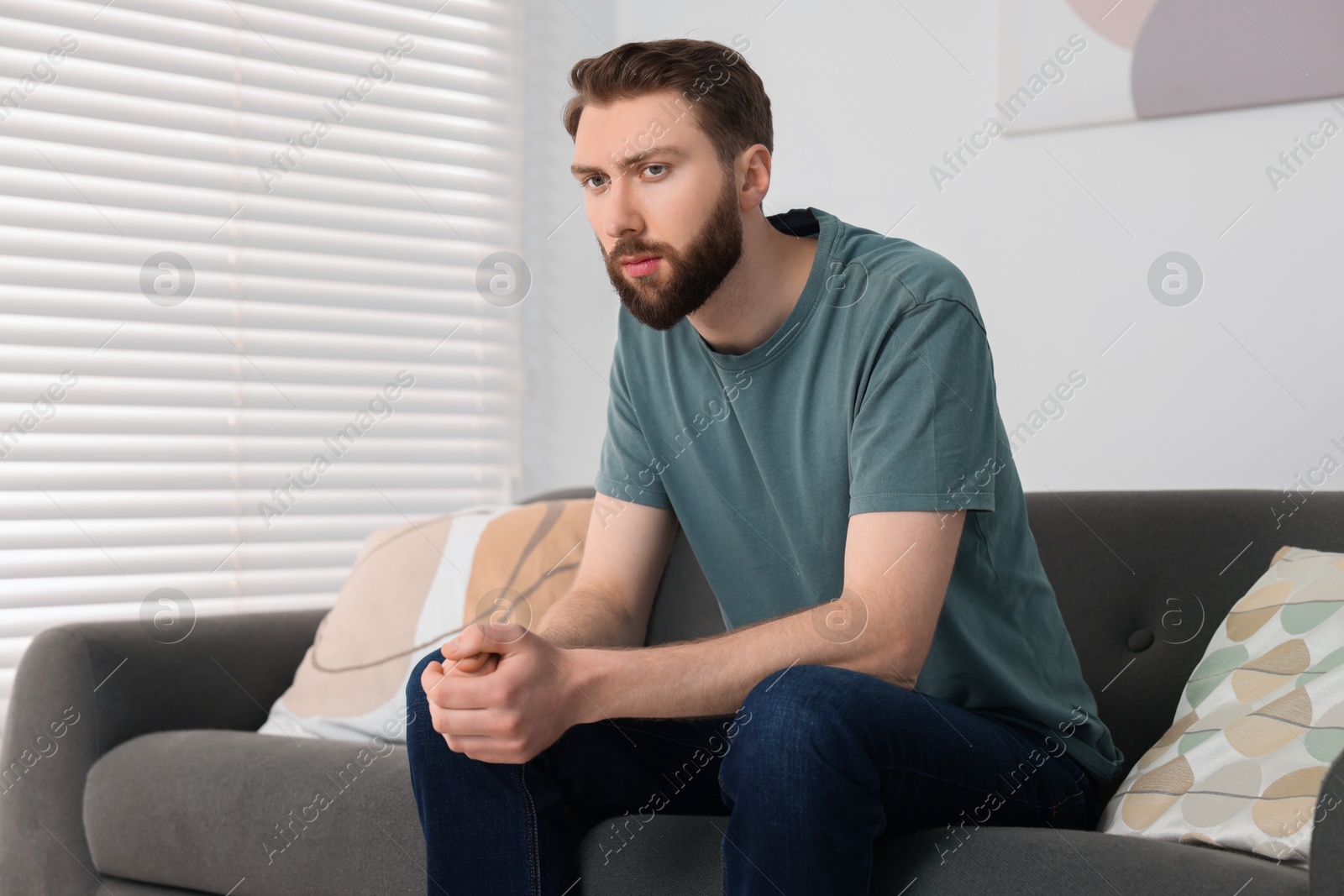 Photo of Loneliness concept. Sad man sitting on sofa at home