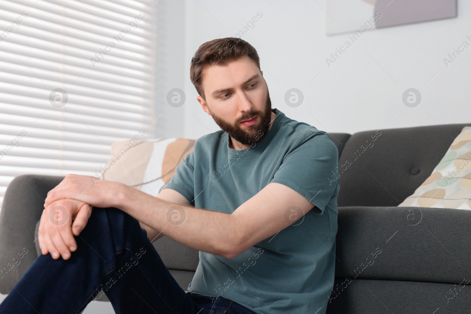 Photo of Loneliness concept. Sad man sitting on floor at home