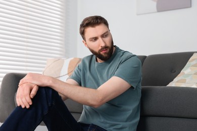 Photo of Loneliness concept. Sad man sitting on floor at home