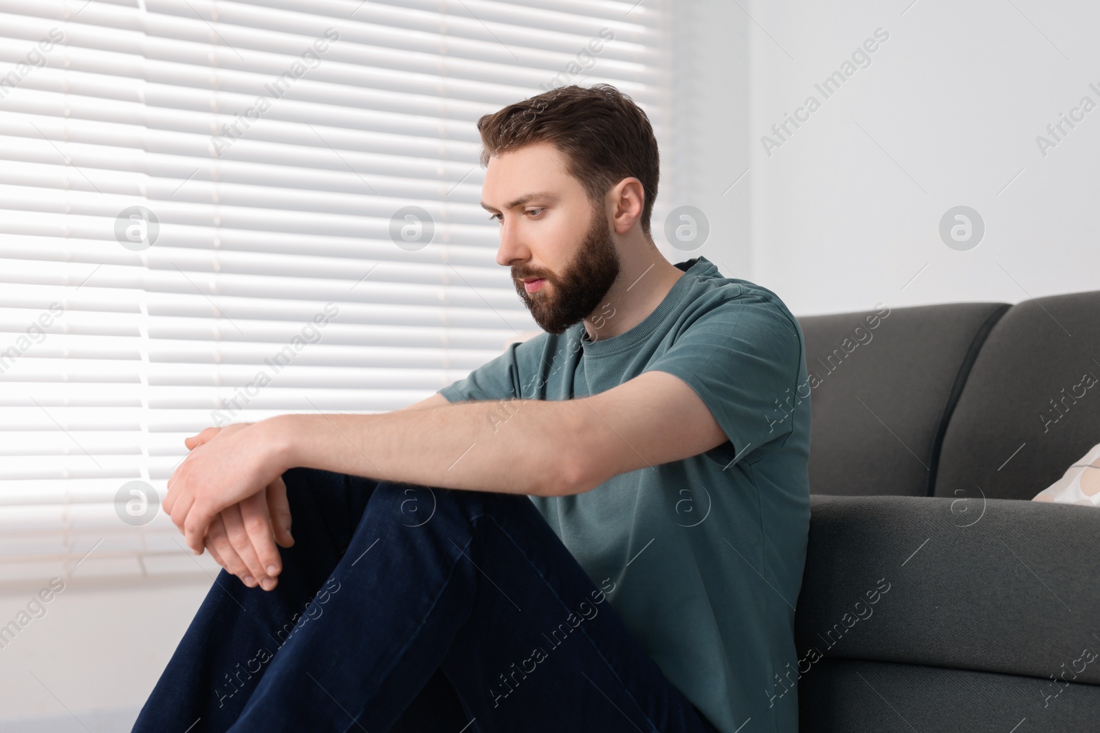 Photo of Loneliness concept. Sad man sitting on floor at home