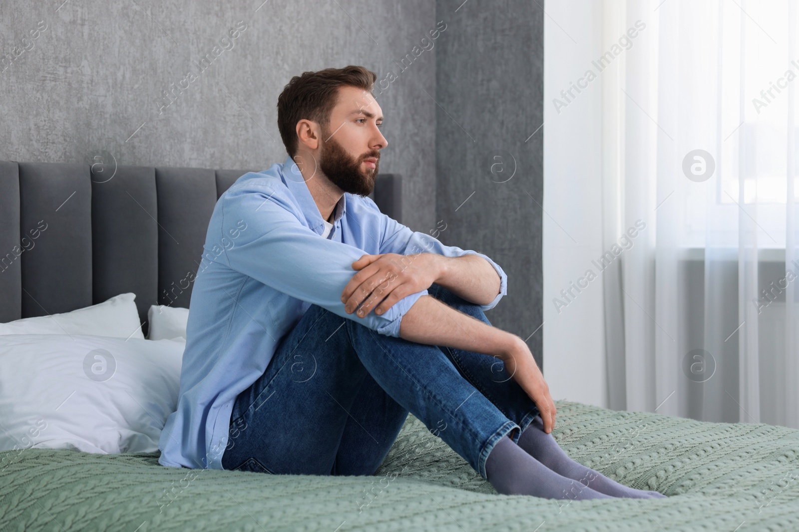 Photo of Loneliness concept. Sad man sitting on bed at home