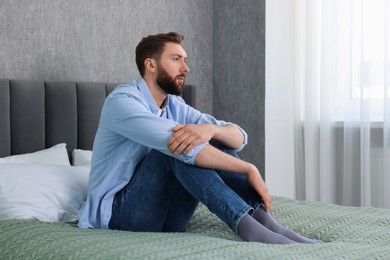 Photo of Loneliness concept. Sad man sitting on bed at home