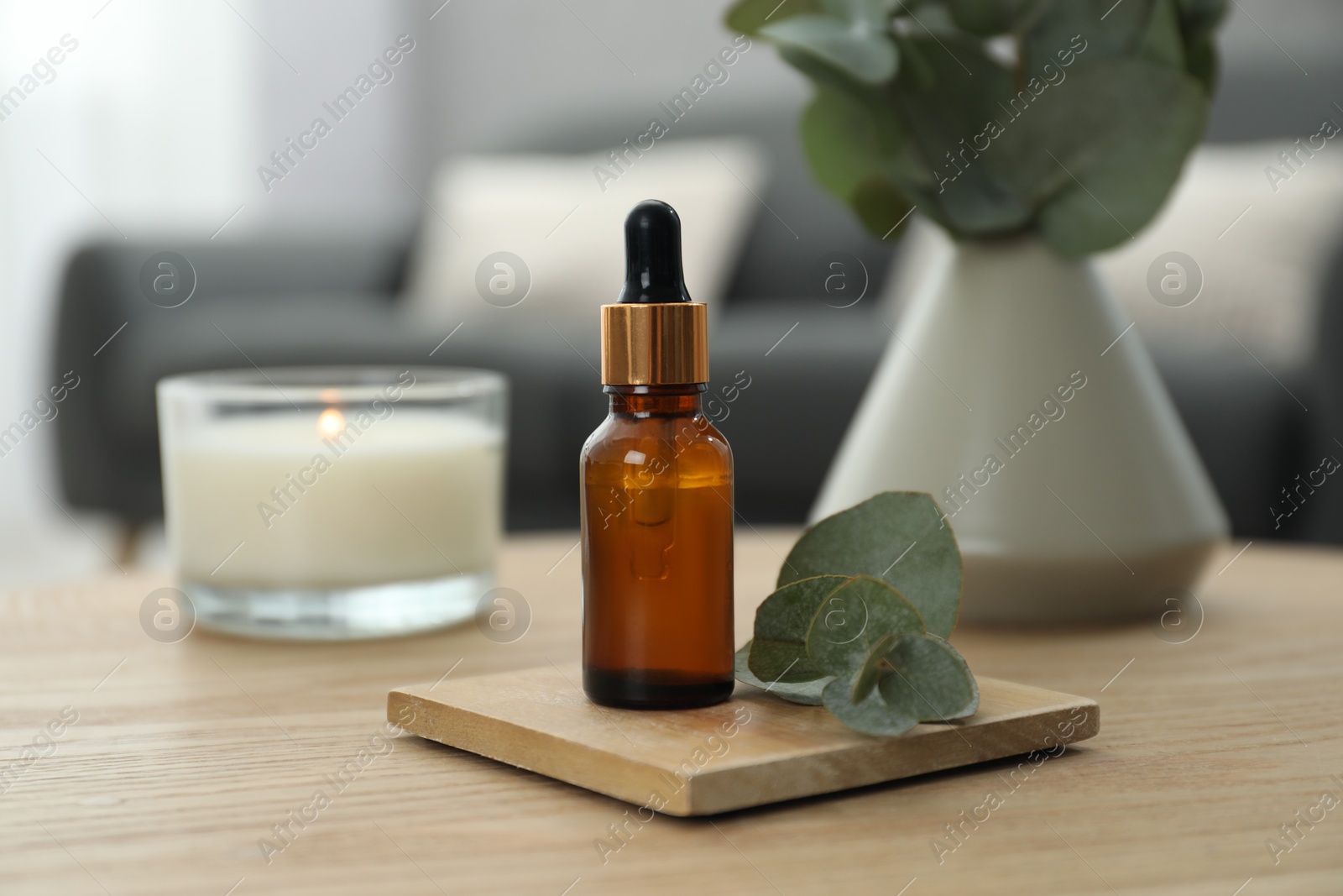 Photo of Aromatherapy. Bottle of essential oil and eucalyptus leaves on wooden table