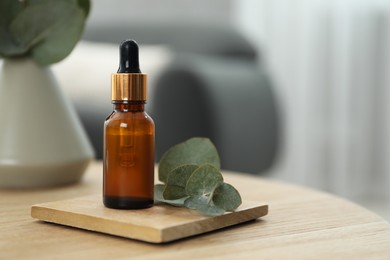Photo of Aromatherapy. Bottle of essential oil and eucalyptus leaves on wooden table, space for text