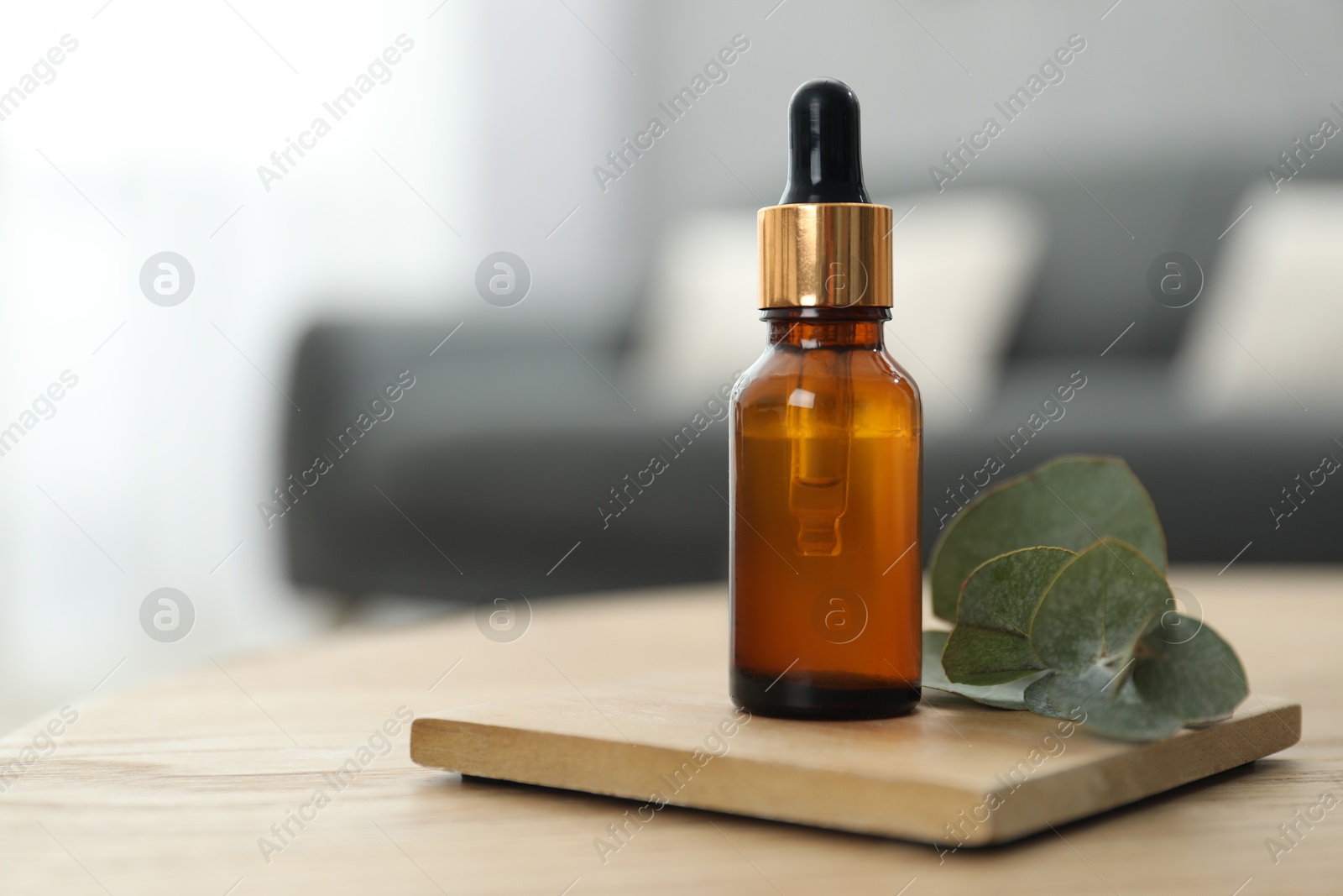 Photo of Aromatherapy. Bottle of essential oil and eucalyptus leaves on wooden table, space for text