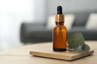 Aromatherapy. Bottle of essential oil and eucalyptus leaves on wooden table, space for text