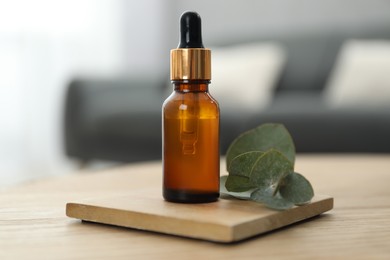 Aromatherapy. Bottle of essential oil and eucalyptus leaves on wooden table