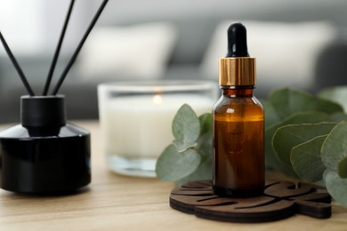 Photo of Aromatherapy. Bottle of essential oil, reed air freshener and eucalyptus leaves on wooden table