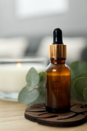 Photo of Aromatherapy. Bottle of essential oil and eucalyptus leaves on wooden table